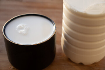 Glass of milk standing on old wooden table. Black glass with white milk. Black glass with white milk on the table