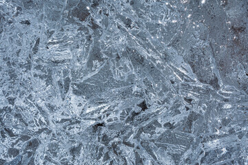 Texture of blue structural ice with kinks and cracks. Frozen water abstract background