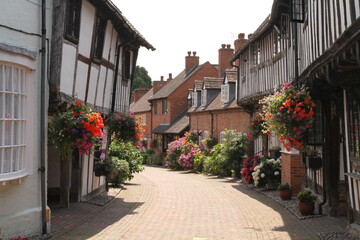 Fototapeta na wymiar Half Timbered, Black & White Houses in Shakespeare's Country Malt Mill Lane Alcester Warwickshire, UK. Hanging baskets & floral blooms in High Summer.