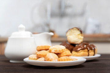 Plate of cookies and eclairs, sugar bowl in the background. Sweet dessert. Baking for tea