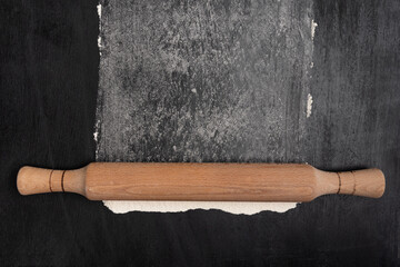 Wooden rolling pin and flour on gray background, top view