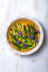 Green asparagus, sweet peas Tart with edible chives flowers or blossoms. Seasonal spring dinner, overhead view.