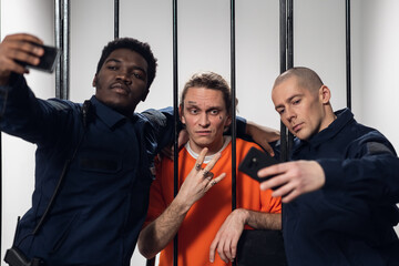 Warders in a high-security prison mock a prisoner in a cell, take photos with him on a smartphone.