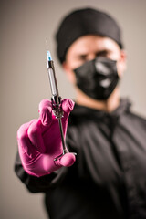 dentist posing with syringe, uniform, gloves, teeth and other instruments