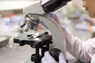Close-up of female scientist examining samples through the microscope in the laboratory