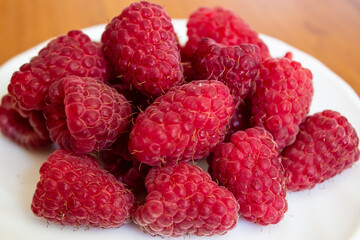 Ripe juicy red raspberries in a plate, close up macro. Healthy eating concept