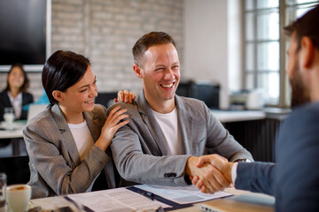 Happy young couple make a deal with their personal financial advisor in bank - obrazy, fototapety, plakaty