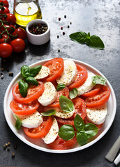 Caprese is a tomato and mozzarella appetizer. Traditional Italian salad on a concrete background with space for text.