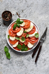 Caprese is a tomato and mozzarella appetizer. Italian salad on the kitchen table with space for the text. View from above.