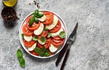 Caprese is a tomato and mozzarella appetizer. Italian salad on the kitchen table with space for the text. View from above.