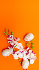 White Easter eggs and flowers on orange background. Spring holidays concept