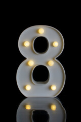 Number 8 (eight) of white plastic, with bright round lights, with a dark black background, on a shiny black reflective floor