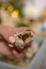 Mini cupcake cookie with chocolate filling, in focus, held by a female hand, with blurred background