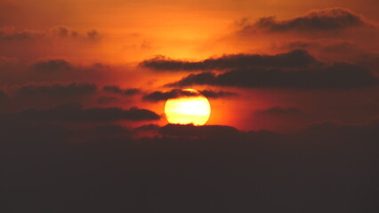 Sunset in the maldives with sun partly covered by clouds