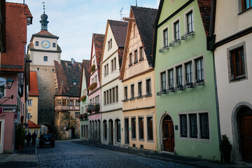 Fototapeta na wymiar Medieval narrow street, colorful renaissance and gothic historical buildings, White Tower or Weisser Turm, sunny autumn day, old town, Rothenburg ob der Tauber, Bavaria, Germany