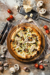 Italian pizza with chicken and mushrooms on a wooden board.