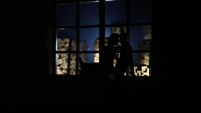 Beautiful view of a miniature city at night from window of dollhouse. Romantic couple at window. Artwork table decoration with handmade realistic dollhouse. Selective focus.