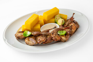 Grilled quails in a sauce with vegetables and herbs. Gentle, diet poultry meat. Banquet festive dishes. Gourmet restaurant menu. White background.