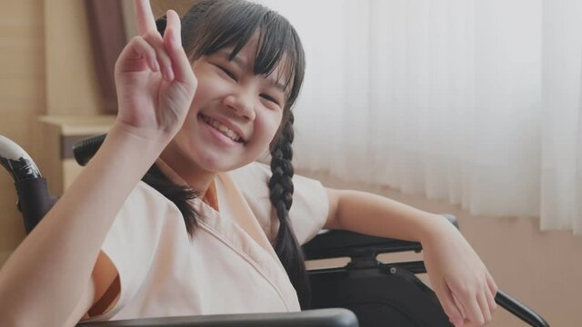 Portrait of Asian cheerful girl sitting on wheelchair in hospital.