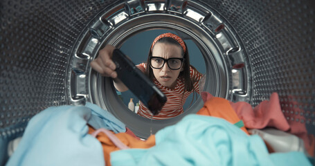 Fototapeta na wymiar Woman finds her smartphone in the washing machine
