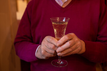hand of an old man holding a glass of sparkling wine in his hands