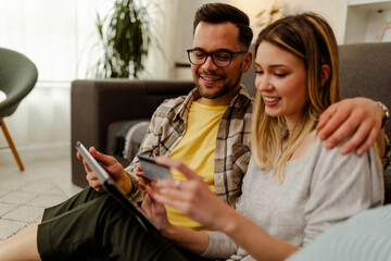 Image of excited cheery young loving couple at home on floor near sofa using laptop computer.