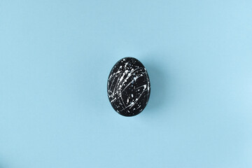 One black egg with white flecks on a blue background. Copy The Space. Flat layer. Easter. minimum. banner.