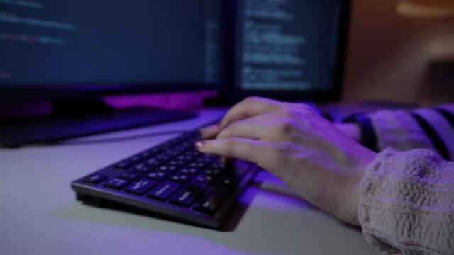 Young female programmer is sitting in office and coding new software typing on keyboard in macro. Closeup view of womans hands writing html lines. Work process of an employee in IT support. Online job