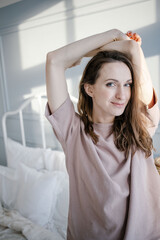 Fototapeta premium woman pulls hands up standing bed