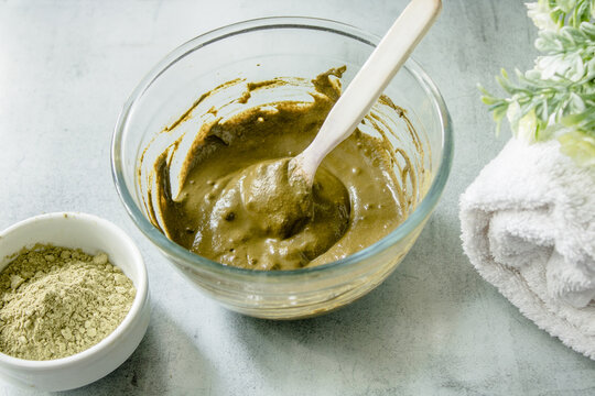 Henna dry powder, glass bowl with henna rehydrated, white terry towel on a marble mat. Home hair coloring by  organic eco-friendly paint.