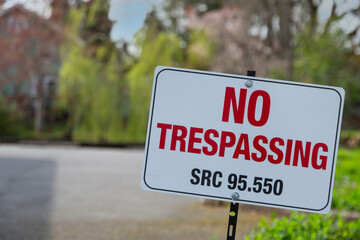 No trespassing sign, quoting SRC code 95.550, on a spike with an out of focus background