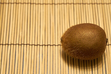 Ripe brown kiwi on a straw background.