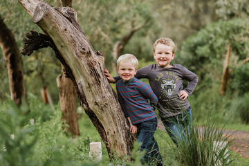 Naklejka na ściany i meble Two boys leaning against tree smiling in the Australian bush