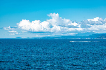 blue skies and clouds with boat passing on ocean