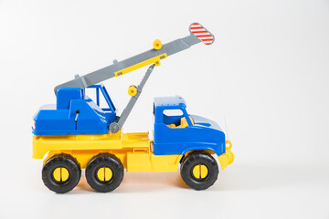 Plastic car. Toy model isolated on a white background. Yellow-blue truck crane with an arrow to lift the load.