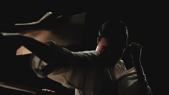 A young woman in kimono breaks a wooden board with her hand. Slow motion