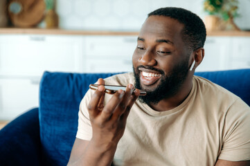Close-up of handsome friendly confident african american guy sitting in living room on sofa talking...