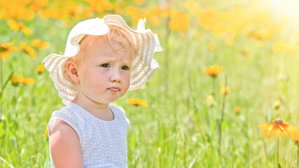 Portrait of beautiful little girl on background of yellow flowers in a meadow. happy childhood in nature. Walking while quarantine away from people