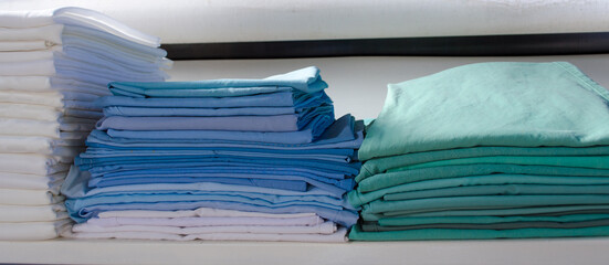 Stacked green and blue surgical clothing in an industrial laundry.
