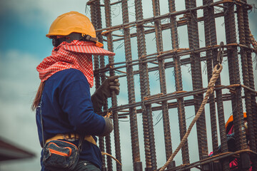Female laborers are climbing on the scaffolding to assemble the steel structure columns.