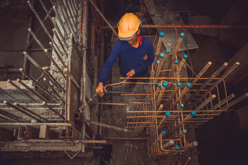 Construction worker undoing formwork studs in basement concrete wall