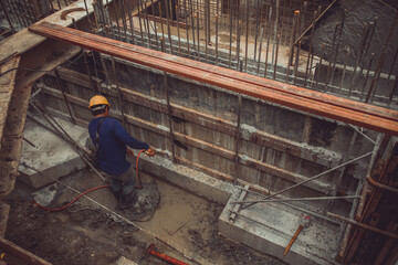 Construction worker undoing formwork studs in basement concrete wall