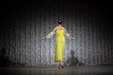 Girl in a yellow dress.The girl is dancing on stage.  Dancer's movements in the assembly hall....