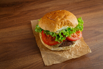 Delicious hamburger on wooden background. Burger with tomato, lettuce, meat and cheese.