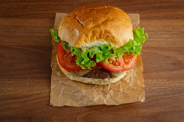 Delicious hamburger on wooden background. Burger with tomato, lettuce, meat and cheese.