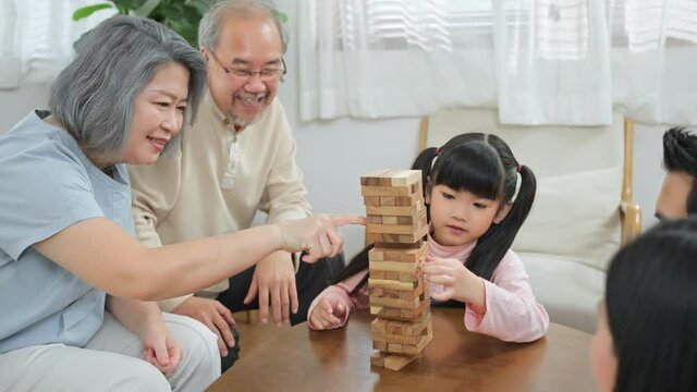 Asian big family playing jenga together at home in the living room.