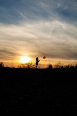 Girl with red balloon at sunset