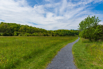 A gravel covered path lines a grassy field and leads into the foothills of the Shenandoah Mountains.