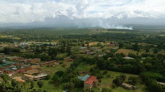 Aerial view over a town towards burning fields of rural sunny Africa - drone shot