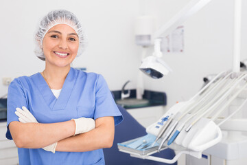 Portrait of a positive young female dentist in uniform with crossed hands at the dental office